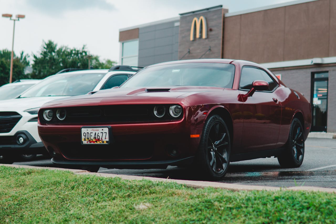 Red Dodge Challenger parked in a McDonald's lot, showcasing its sleek design.