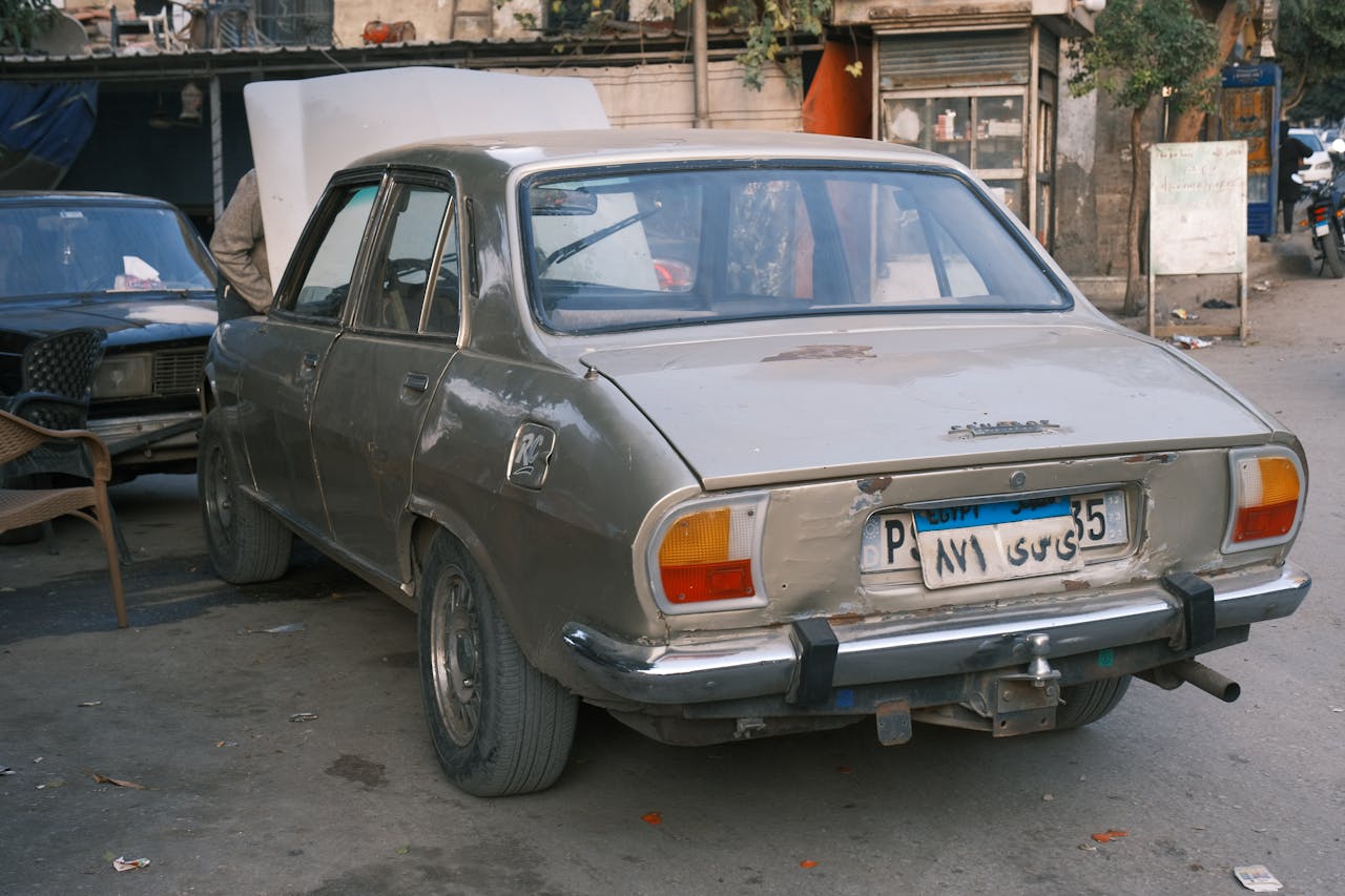 A vintage sedan parked on a busy urban street with a visible license plate.